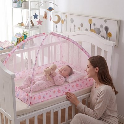 Moustiquaire lit bébé  avec un bébé qui joue à l'intérieur au berceau.